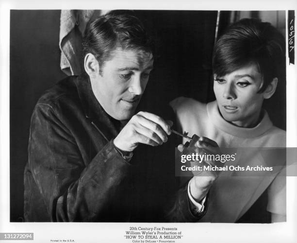 Peter O'Toole manages to spring the lock that hold him and Audrey Hepburn captive in a janitor's closet in a scene from the film 'How To Steal A...