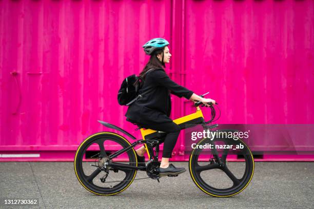 ung kvinna som cyklar med rosa bakgrund. - elcykel bildbanksfoton och bilder
