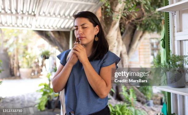 young woman smelling of essential oil in outdoor tent - essence day stock pictures, royalty-free photos & images