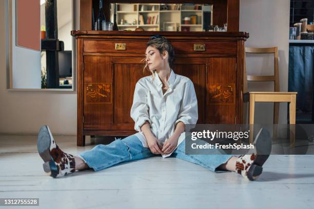 nieuw normaal concept: jonge mooie kaukasische vrouw die op de witte vloer zit, die neer terwijl het denken over pre-covid era (horizontaal) kijkt - female soles stockfoto's en -beelden