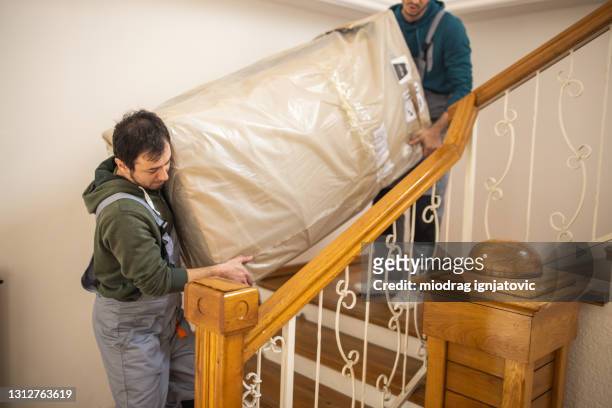 movers carrying furniture in client's house - moving service imagens e fotografias de stock