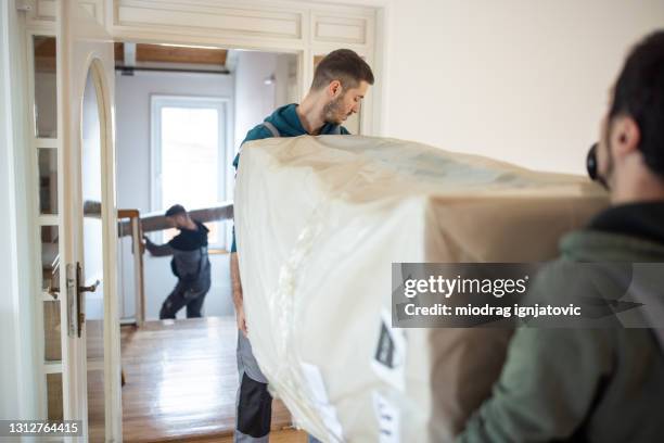 déménageurs professionnels apportant de nouveaux meubles dans la maison - lourd photos et images de collection