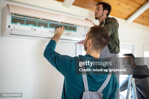 Repairman team installing air conditioner Repairman team installing air conditioner