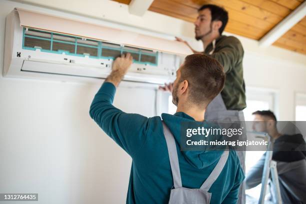 repairman team installing air conditioner - ventilation stock pictures, royalty-free photos & images