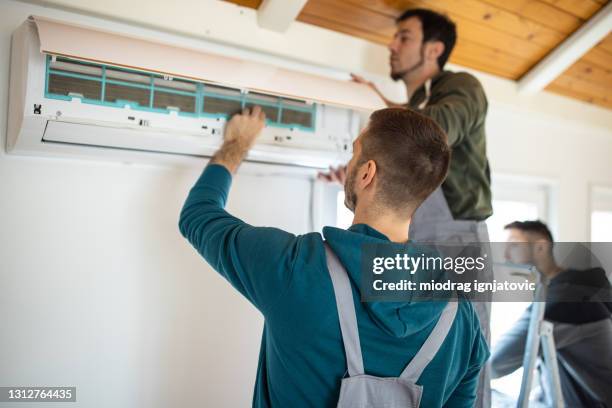 repairman team installing air conditioner - hvac service stock pictures, royalty-free photos & images