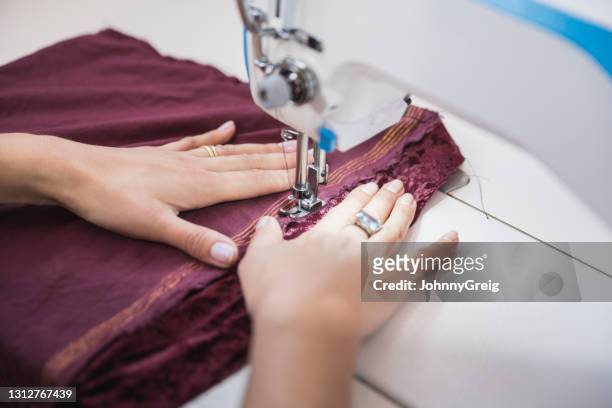 tailor stitching maroon fabric on sewing machine - hem stock pictures, royalty-free photos & images