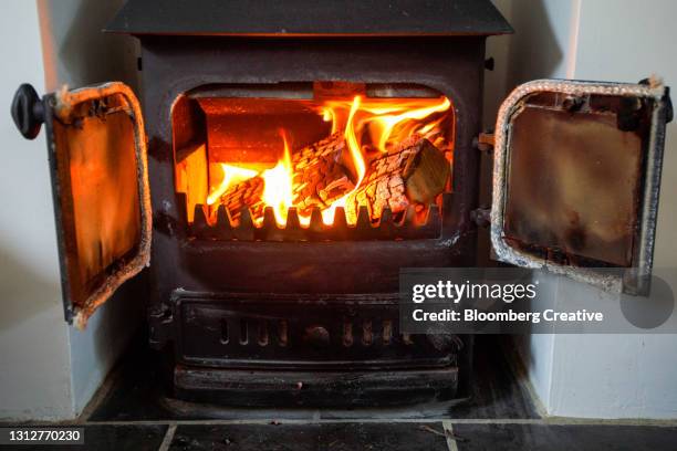 logs burning on a wood burner - quemador fotografías e imágenes de stock