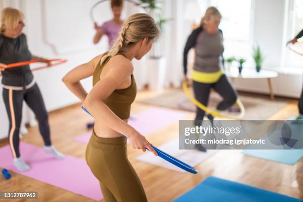 aerobic-instruktor und senioren üben mit hula-hoop während des aerobic-kurses - gymnastikreifen stock-fotos und bilder