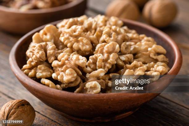 walnuts in brown bowl on wooden table - walnuts stockfoto's en -beelden