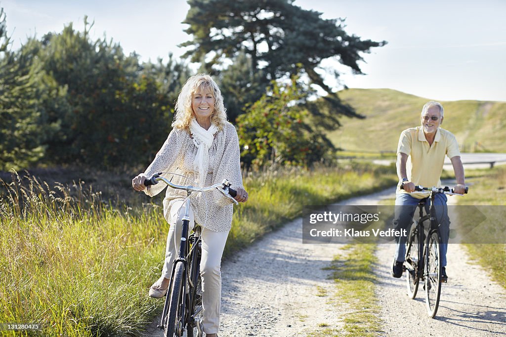 Mature couple bicycling on gravel road