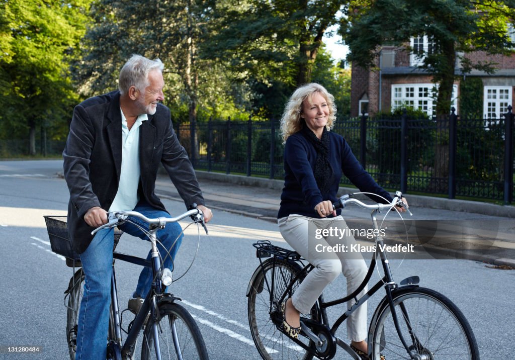 Mature couple cycling in residential neighborhood