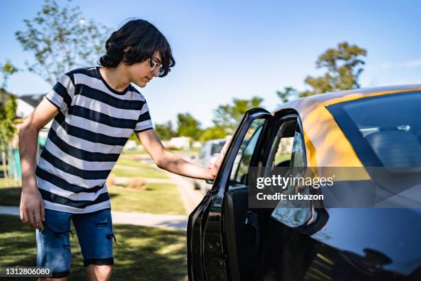 teenage boy opening car door - car door stock pictures, royalty-free photos & images