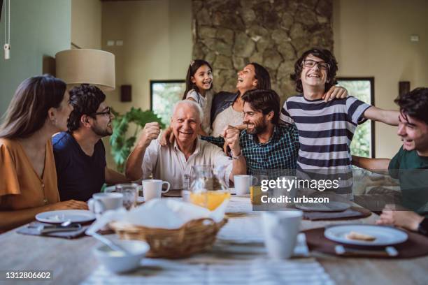 gelukkige grootvader die met zijn familie bij ontbijt wordt omringd - children eating breakfast stockfoto's en -beelden