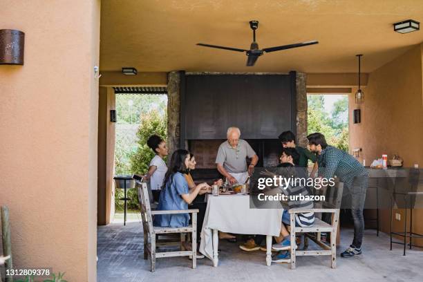 argentine family enjoying traditional asado midday meal - argentina traditional food stock pictures, royalty-free photos & images