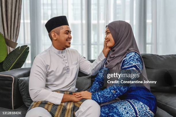 husband patting lovely wife cheek during hari raya celebration - malay couple stock pictures, royalty-free photos & images