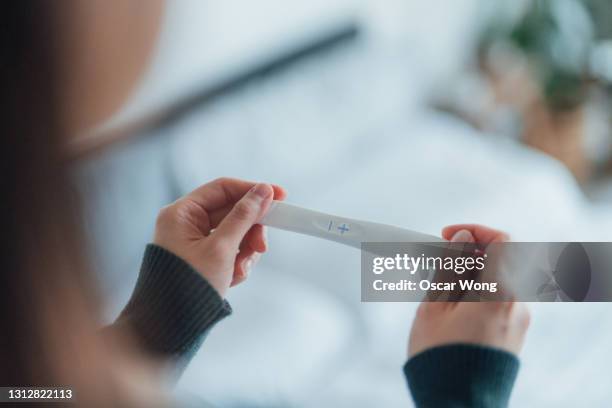rear view cropped shot of unrecognisable woman taking pregnancy test at home - family planning stock pictures, royalty-free photos & images