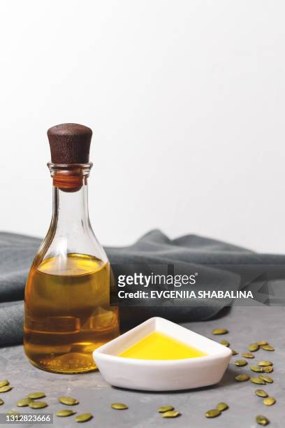 a glass bottle of pumpkin seed oil or linseed oil on a grey and white background with grey textile - black seed oil - fotografias e filmes do acervo