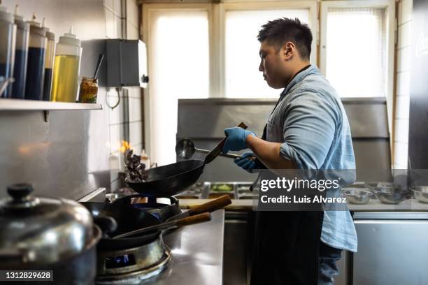 vietnamese chef tossing vegetables flambe in a pan over the burner - stir frying european stock pictures, royalty-free photos & images