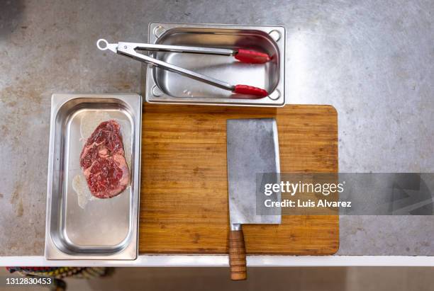 meat cleaver and wooden chopping board in kitchen - pinça utensílio de servir - fotografias e filmes do acervo