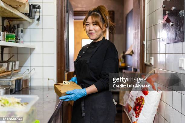 portrait of an asian female preparing food parcel in kitchen - vietnamese ethnicity imagens e fotografias de stock
