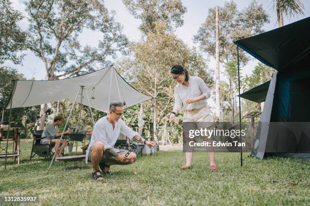 asiatico cinese coppia matura allevare tenda e campo nei boschi - picchetto da tenda foto e immagini stock