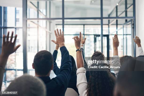 scatto di un gruppo di uomini d'affari che alzano la mano durante una presentazione - domanda foto e immagini stock