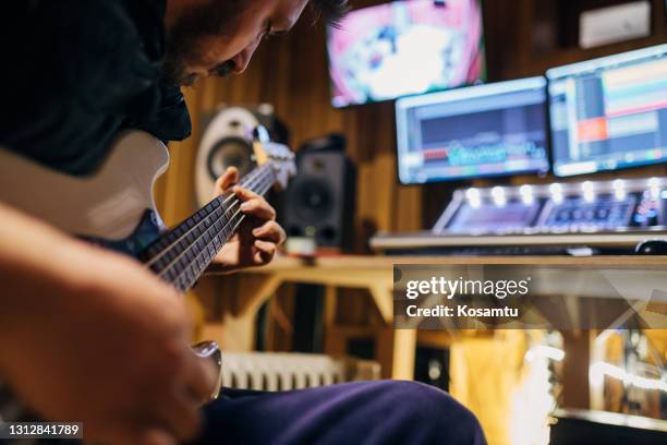 passionerad manlig basistgitarrist, experimenterar med nya musikstilar i inspelningsstudion - bass player bildbanksfoton och bilder