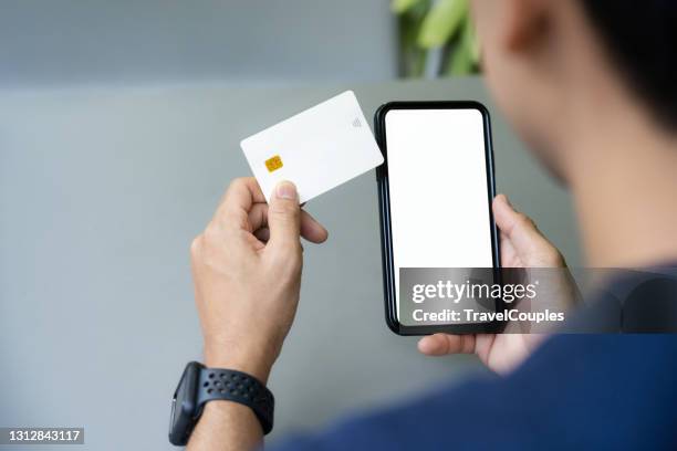 male hands holding credit card and using smart phone. online shopping concept. network connection on mobile screen. payments online. - credit card stock pictures, royalty-free photos & images