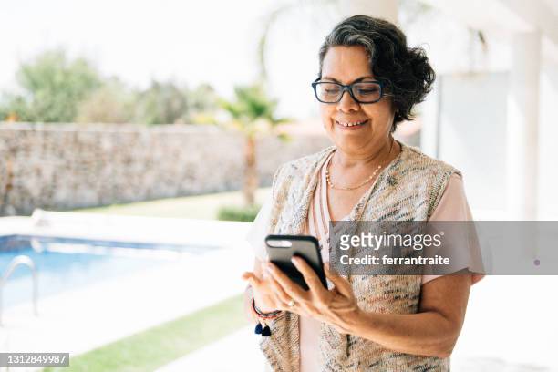 mujer mayor usando teléfono inteligente - mujer mexicana fotografías e imágenes de stock