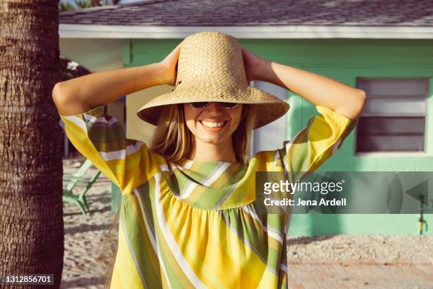 retro woman on vacation smiling with vintage 1950s style straw hat and sunglasses - stijlvolle dame stockfoto's en -beelden