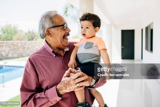 grandfather holding grandson toddler by the swimming pool - grandfather stock pictures, royalty-free photos & images