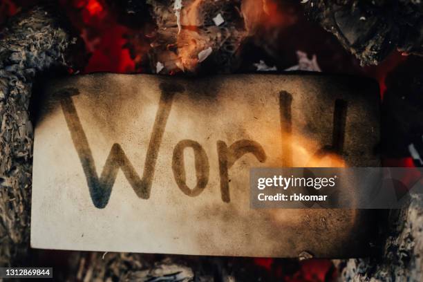 the word world written on white paper burning in a flame of fire. world crash, apocalypse, global pandemic and doomsday concept - epidemic map stock pictures, royalty-free photos & images