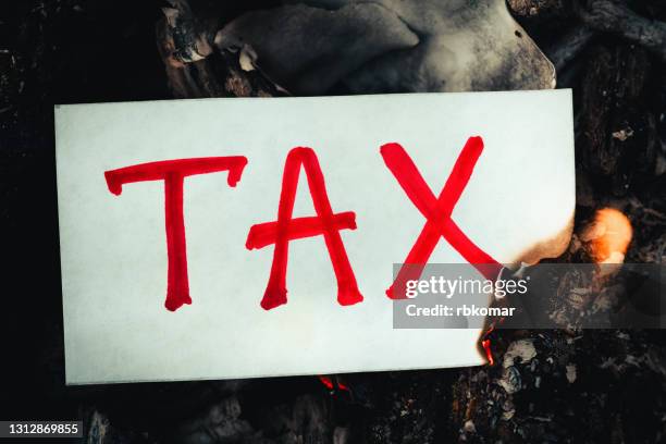 the red word tax is written on white paper burning in a flame of fire. family budget concept, deadline, financial report in time to pay debt - expense fraud stock pictures, royalty-free photos & images