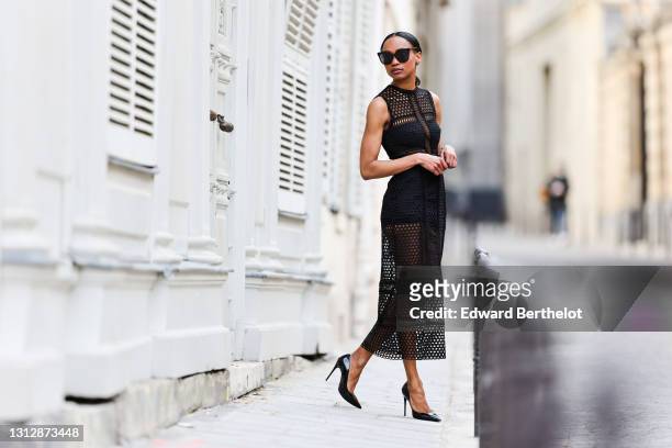 Emilie Joseph @in_fashionwetrust wears sunglasses, a black midi length crochet / see through sleeveless dress by Self Portrait, black pointed high...