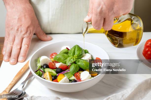 fresh salad with cucumbers, tomatoes, onions, black olives and feta or mozzarella cheese, with olive oil and celery - mediterraanse gerechten stockfoto's en -beelden