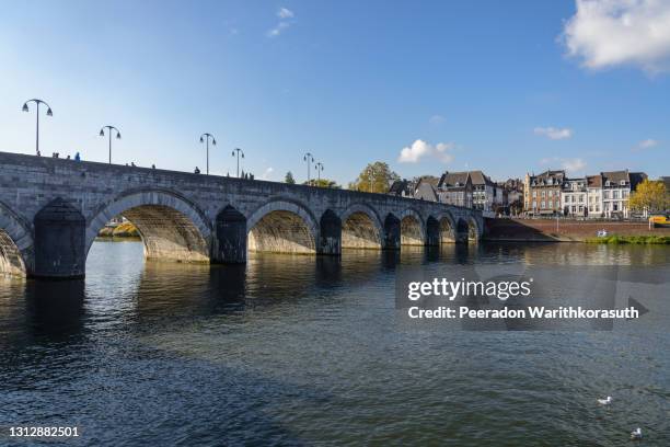 outdoor sunny view of sint servaasbrug, historical footbridge cross meuse river, and background of cityscape in maastricht, netherlands. - limburgo países bajos fotografías e imágenes de stock