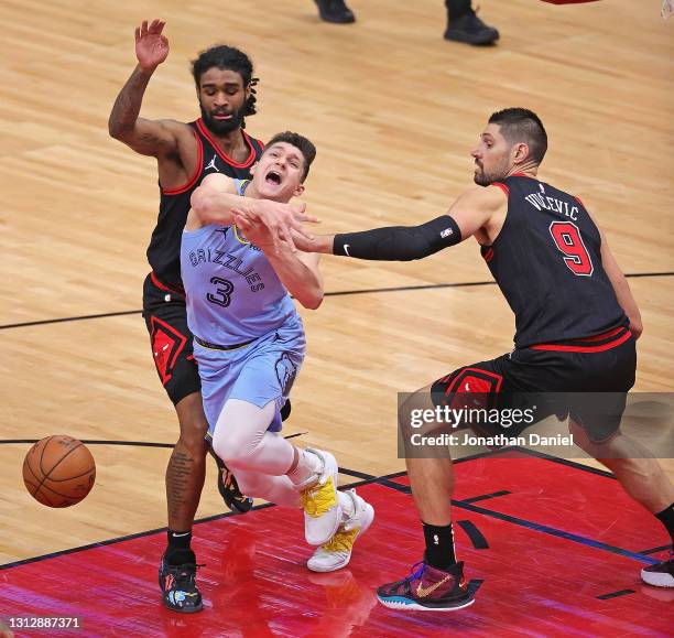 Grayson Allen of the Memphis Grizzlies is fouled by Nikola Vucevic of the Chicago Bulls as he drives against Coby White at the United Center on April...