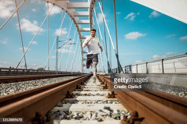 jeune homme athlétique heureux exécutant sur le chemin de fer. - sprint photos et images de collection