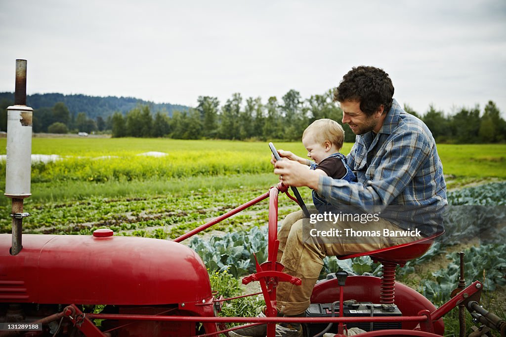 Farmer and baby boy sitting on tractor in field