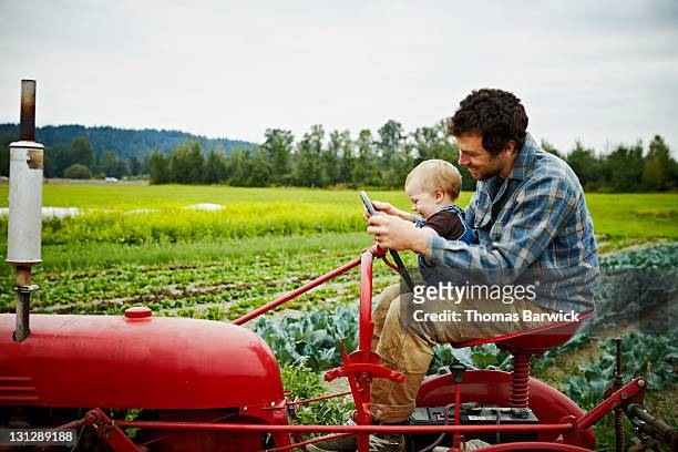 Farmer and baby boy sitting on tractor in field