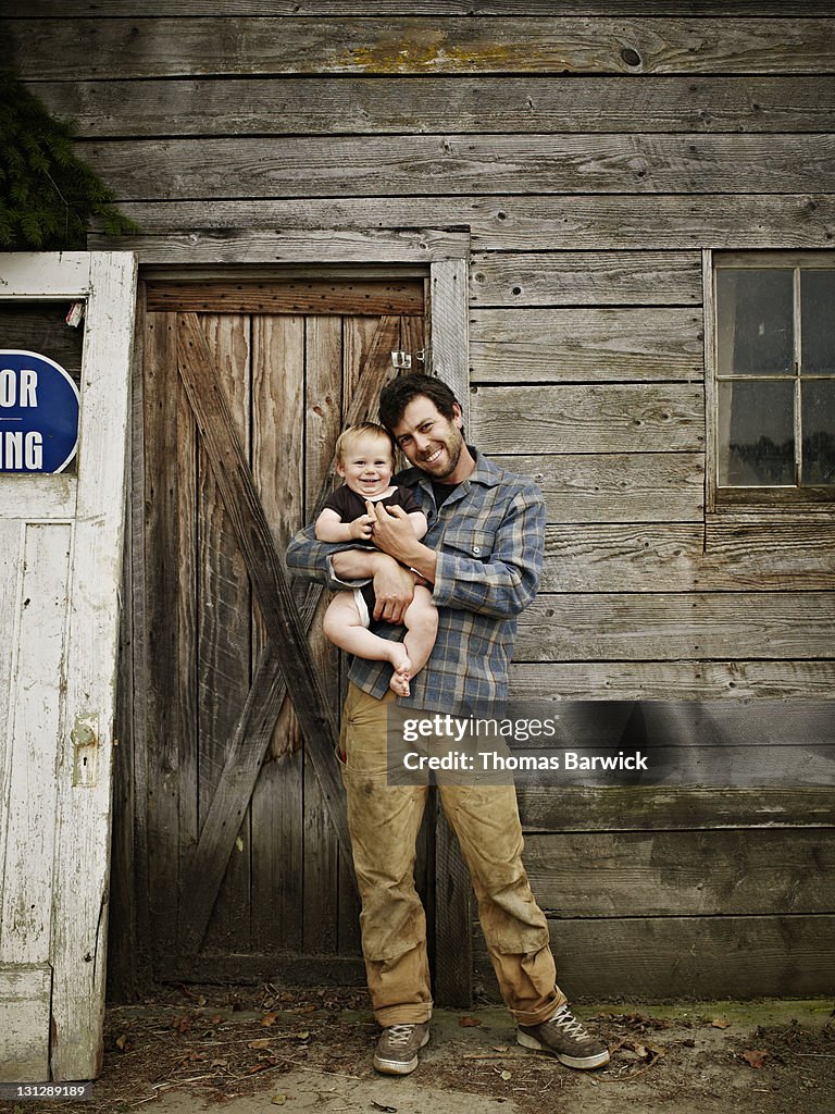 Farmer holding smiling baby boy