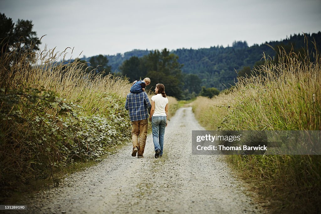 Family walking on dirt road rear view