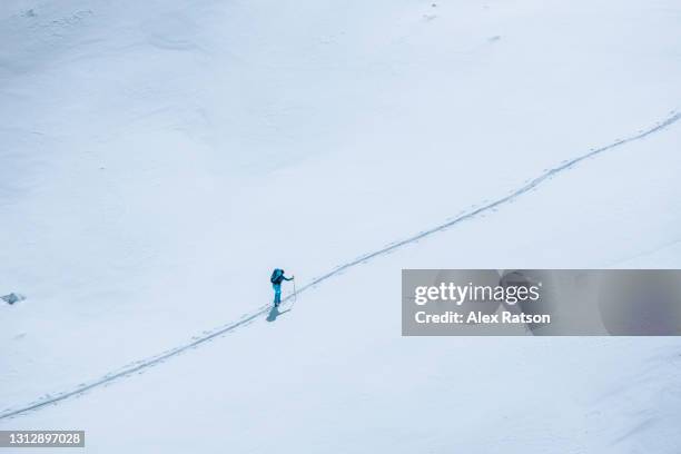 aerial view of backcountry skier traversing across expansive glacier in tantalus mountain range - cross country skiing tracks stock pictures, royalty-free photos & images