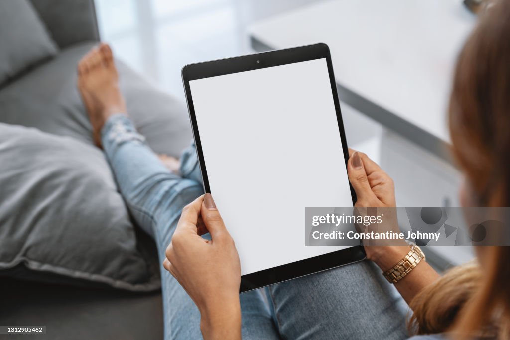 Over The Shoulder View of A Woman Using Digital Tablet With Blank White Screen Mock Up