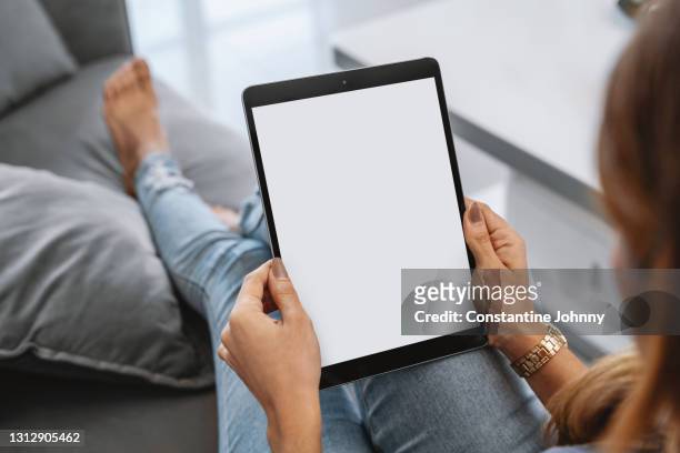 over the shoulder view of a woman using digital tablet with blank white screen mock up - digital tablet stock pictures, royalty-free photos & images