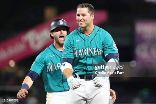 Ty France of the Seattle Mariners is greeted by Mitch Haniger after hitting a walk-off double in the ninth inning against the Houston Astros at...