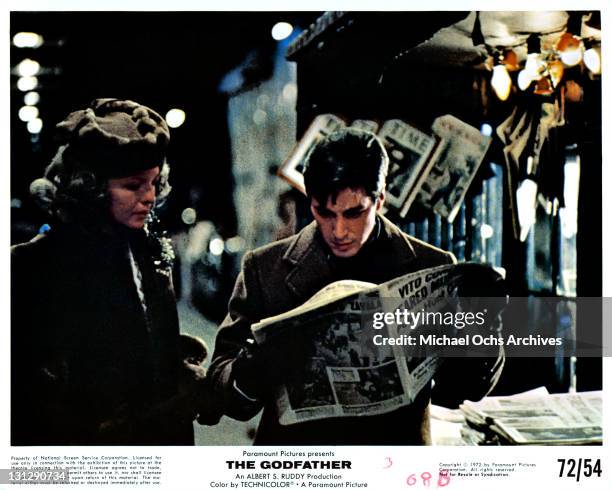 Unidentified woman standing next to Al Pacino as he reads the paper in a scene from the film 'The Godfather', 1972.