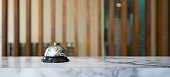 Closeup of a silver service bell on hotel reception desk.