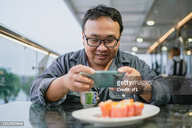 拍攝美食的超重男人 - fat asian man stock pictures, royalty-free photos & images