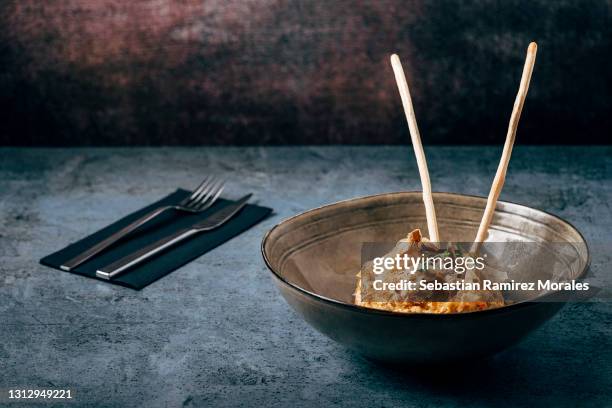 russian salad in a ceramic bowl with two toasted bread sticks, bluestone base and dark background. - potato salad stock-fotos und bilder